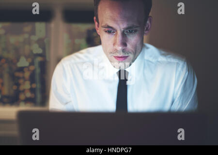 Close up di imprenditore lavoro straordinario su computer, fine lavoro notturno Foto Stock