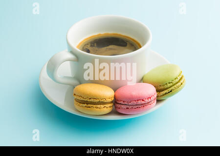 Gustosi dolci macarons e tazza di caffè. Amaretti su sfondo blu. Foto Stock