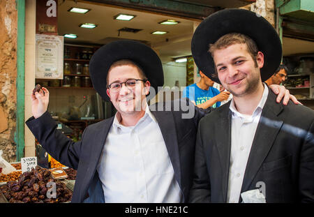 Amici, mostra una data, gli Ebrei Ortodossi, in Mahane Yehuda Market, Gerusalemme, Israele. Foto Stock