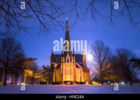 Bella cattedrale chiesa visibile su un inverno nevoso notte con luna incandescente in background Foto Stock