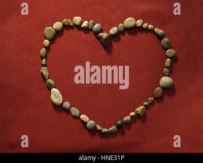 Un cuore di pietre su raso rosso - California di giada e le Pietre di luna Foto Stock