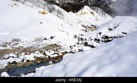 Primo piano della pietra e del flusso nella nebbia Noboribetsu Onsen neve invernale del parco nazionale di Jigokudani, Hokkaido, Giappone Foto Stock