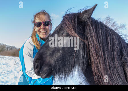 Ritratto di donna caucasica con Frisone cavallo in inverno la neve Foto Stock