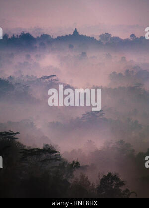 Il sole sorge su una mattinata nebbiosa oltre il tempio Borobudur vicino a Yogyakarta, Indonesia. Foto Stock