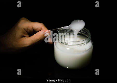 Uomo con un cucchiaio per un barattolo di mastice colla Foto Stock