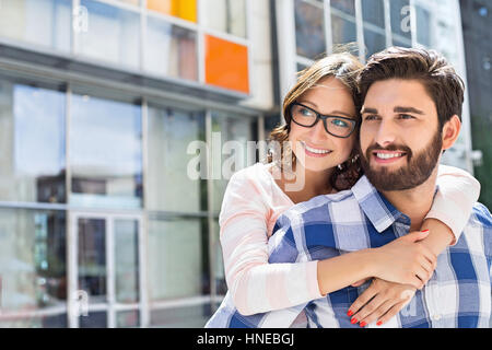 Amare l uomo donna piggybacking in città Foto Stock