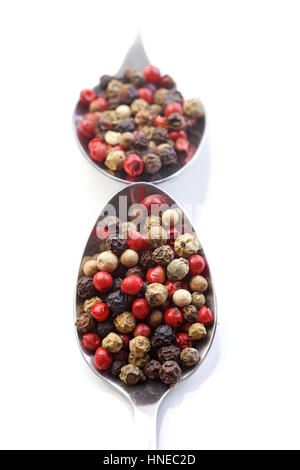 Grani di pepe sul cucchiaio su sfondo bianco Foto Stock