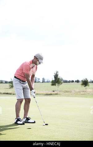 Lunghezza intera di uomo di mezza età giocare a golf in corso Foto Stock