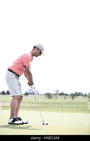 Vista laterale di uomo di mezza età giocare a golf in corso Foto Stock