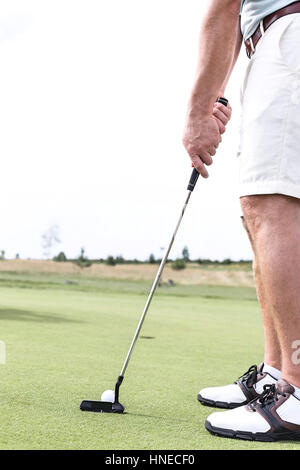 Sezione bassa della metà di uomo adulto giocando a golf contro il cielo chiaro Foto Stock