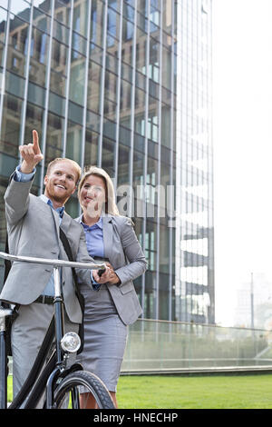Happy businessman mostrando qualcosa di imprenditrice in città Foto Stock