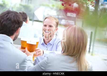 Happy businessman tostare il bicchiere da birra con i colleghi al ristorante all'aperto Foto Stock