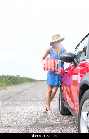 Per tutta la lunghezza della giovane donna il rifornimento auto sulla strada di campagna Foto Stock