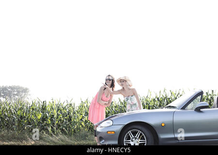 La donna che mostra qualcosa di amico femmina durante la lettura della mappa su cabriolet Foto Stock