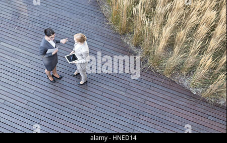 Angolo di alta vista di imprenditrici discutendo mentre sta in piedi sulla pedana Foto Stock