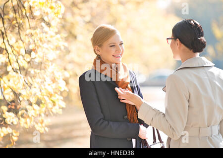 Felice imprenditrice conversando con un collega sul parco sulla giornata di sole Foto Stock