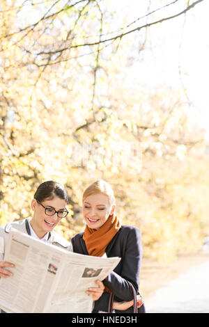 Felice imprenditrici la lettura di giornale insieme al park Foto Stock