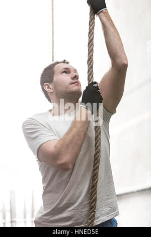 Determinato uomo corda di arrampicata in palestra crossfit Foto Stock