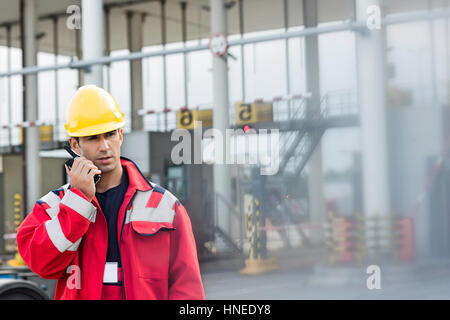 Lavoratore di sesso maschile con un walkie-talkie nel cantiere di spedizione Foto Stock