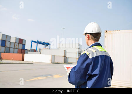 Vista posteriore di mezza età lavoratore con appunti nel cantiere di spedizione Foto Stock