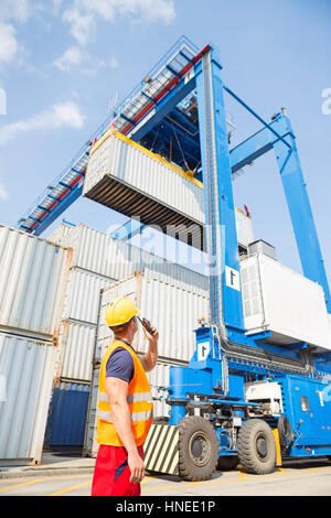 Lavoratore utilizzando un walkie-talkie nel cantiere di spedizione Foto Stock