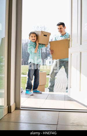 Felice di padre e figlio con scatole di cartone di entrare in casa nuova Foto Stock