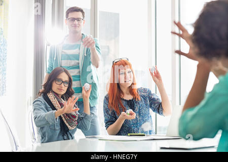 Arrabbiato gli imprenditori lanciando palle di carta su un collega in ufficio creativo Foto Stock