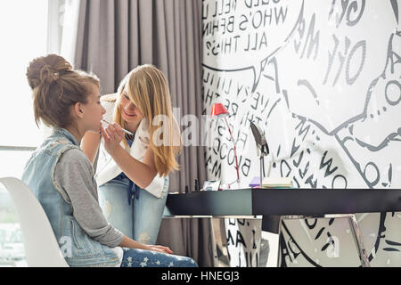 Ragazza adolescente mettendo il rossetto sulla sorella a casa Foto Stock