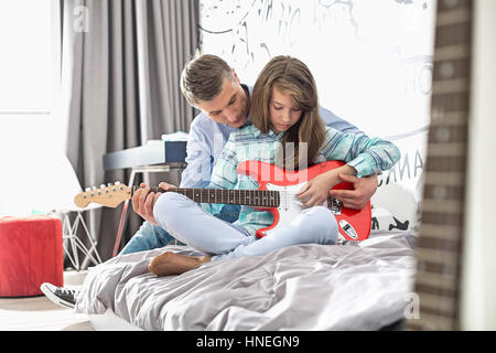 Padre figlia di insegnare a suonare la chitarra a casa Foto Stock