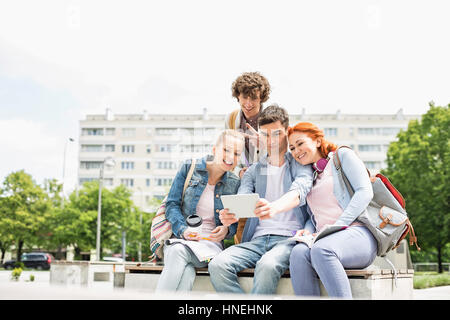 I giovani studenti di fotografare sé stessi attraverso la tavoletta digitale presso il college campus Foto Stock