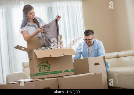 Mid-adulto giovane disimballaggio scatole di cartone nella nuova casa Foto Stock