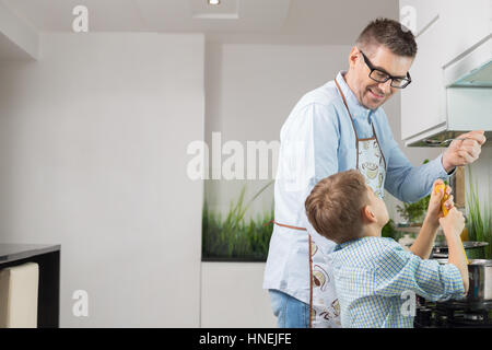 Felice padre e figlio preparare spaghetti in cucina Foto Stock