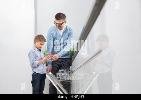 Padre e figlio di immissione di vetro in lavastoviglie in cucina Foto Stock