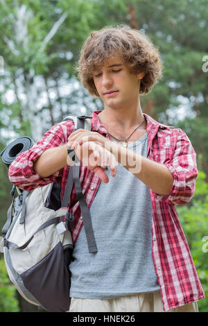 Giovane maschio escursionista controllando il tempo in foresta Foto Stock