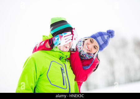 Sorridente giovane donna che copre lo sguardo dell'uomo in inverno Foto Stock