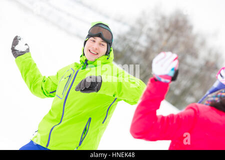 Felice giovane lanciando palle di neve verso la donna Foto Stock