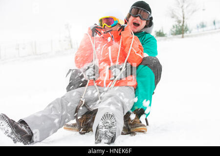 Emozionato coppia giovane slittino nella neve Foto Stock