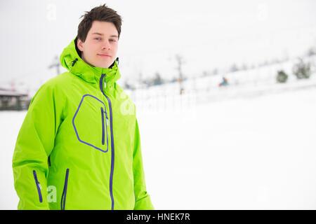 Ritratto di giovane uomo indossando giacca con cappuccio in snow Foto Stock