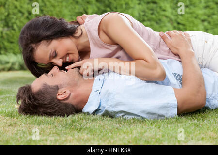 Romantico giovane donna uomo toccano le labbra mentre giacente su di lui in posizione di parcheggio Foto Stock