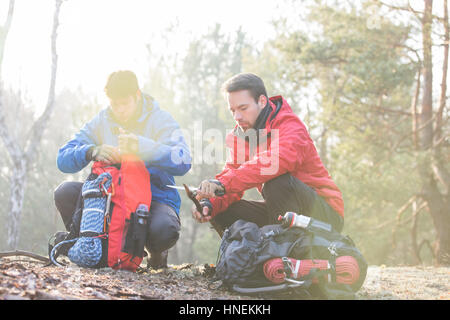 Backpacker maschio con amico whittling legno in foresta Foto Stock