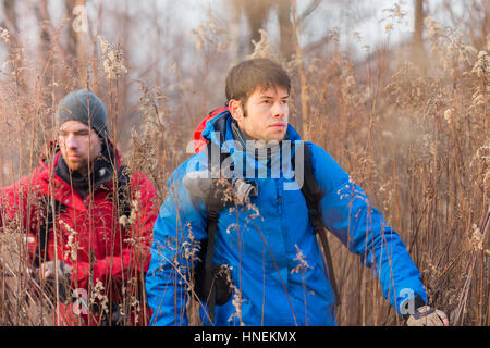 Giovane maschio gli escursionisti a piedi attraverso il campo Foto Stock