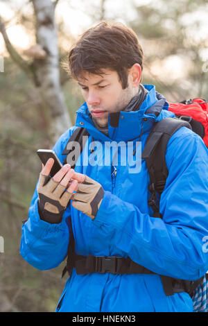 Giovane maschio escursionista utilizzando smart phone in foresta Foto Stock