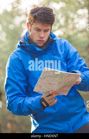 Giovane maschio escursionista mappa di lettura nella foresta Foto Stock