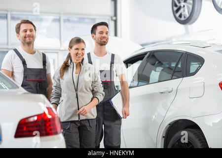 Felice gli ingegneri di manutenzione alla ricerca di distanza in automobile repair shop Foto Stock