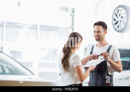 Gli ingegneri di manutenzione con appunti e penna in officina Foto Stock