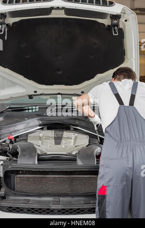 Vista posteriore di ingegnere maschio riparazione auto in automobile repair shop Foto Stock