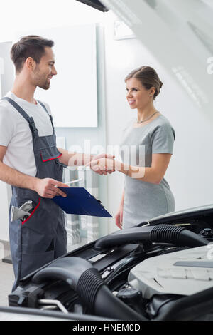 Riparazione giovane lavoratore stringono le mani con il cliente in officina per auto Foto Stock