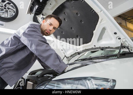 Ritratto di fiducioso maschio lavoratore di riparazione riparazione auto a motore in officina di riparazione Foto Stock