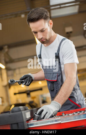 Giovane maschio tecnico manutenzione predisporre strumenti nel cassetto in officina per auto Foto Stock