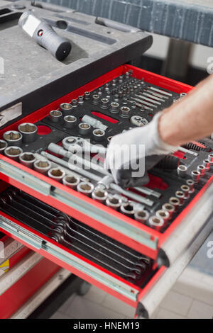 Immagine ritagliata di meccanico maschio tenendo utensile dal cassetto in officina per auto Foto Stock